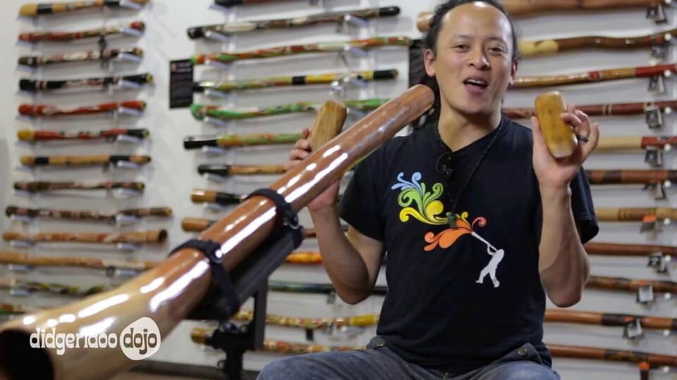 Sanshi playing tapping sticks with a didgeridoo on a stand